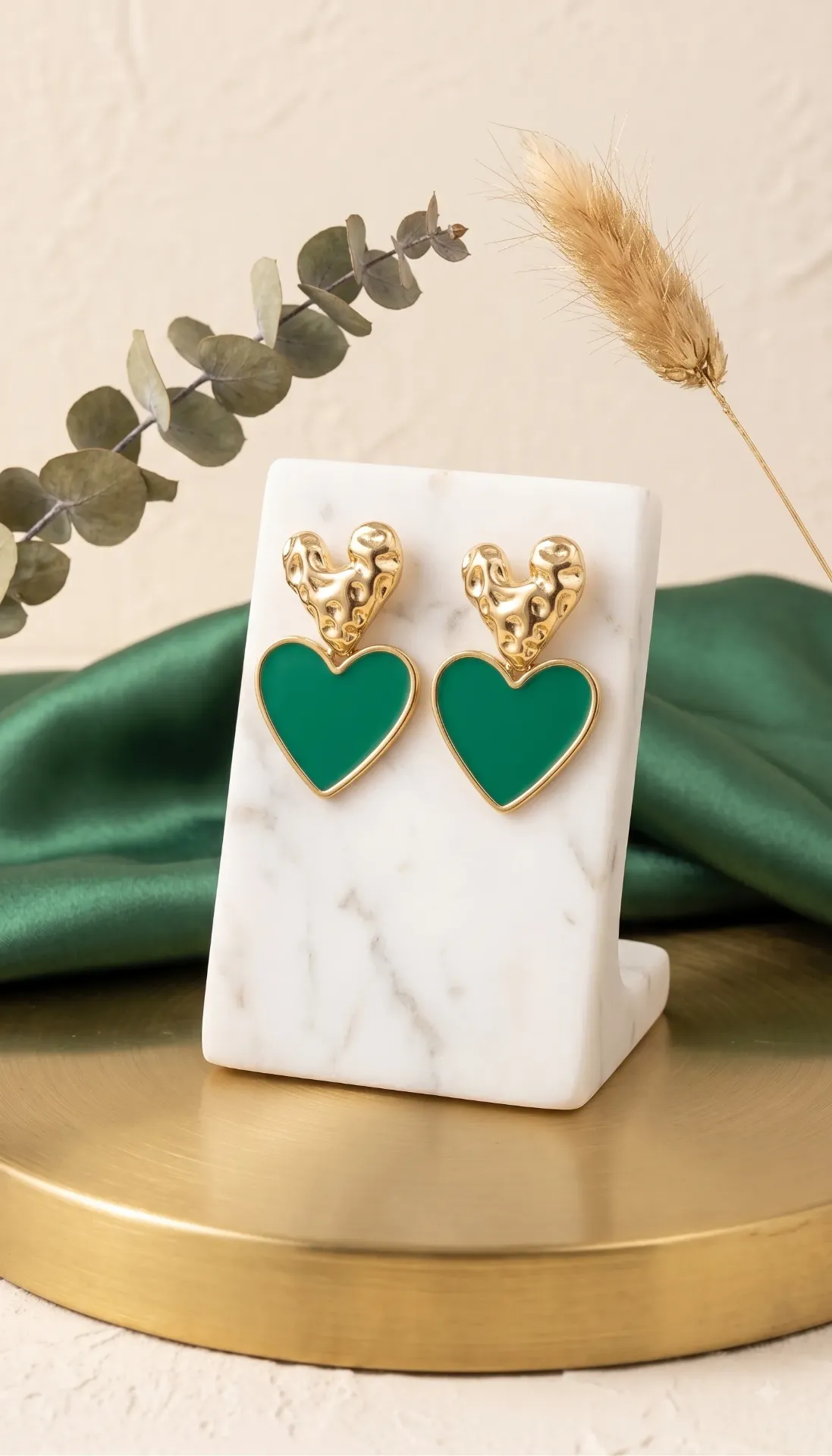 Elegant gold-tone earrings featuring sculpted heart tops paired with glossy emerald-green heart drops